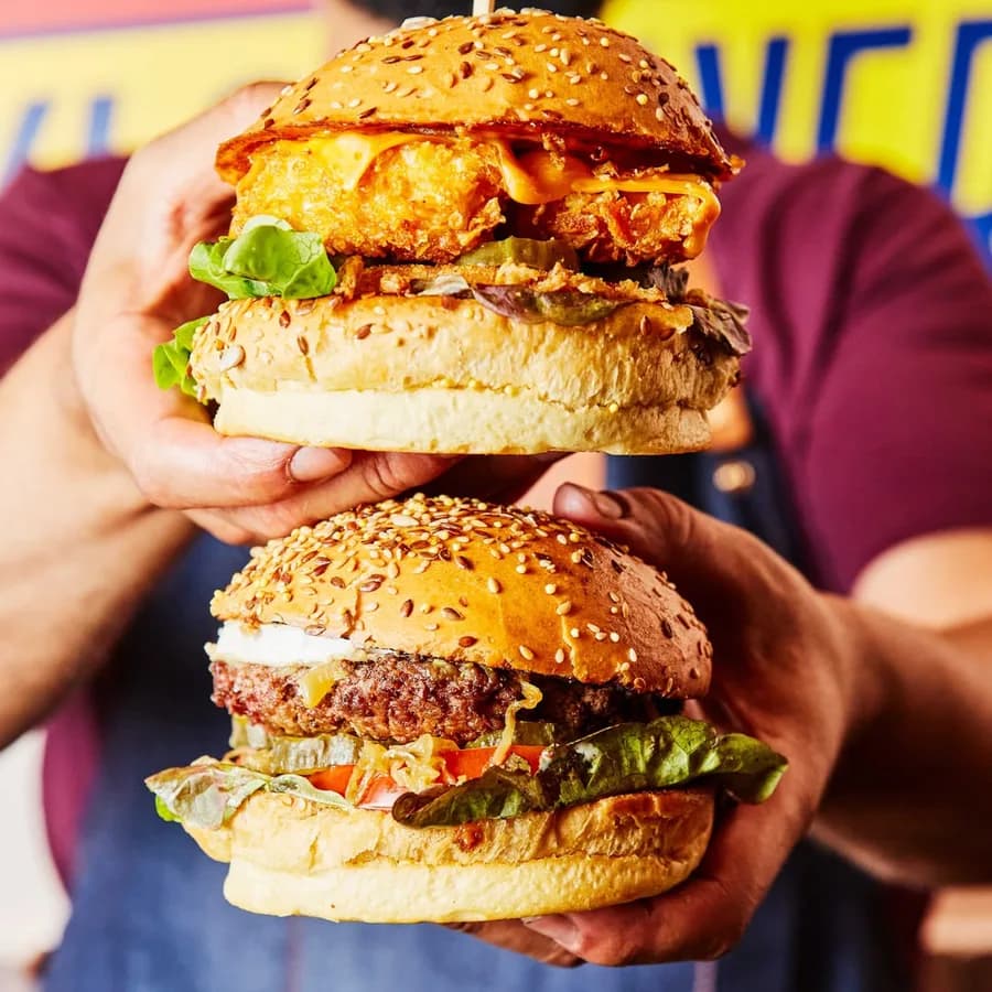 Deux burgers généreux tenus en main